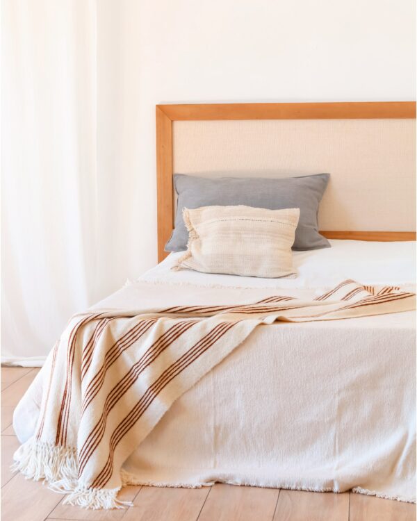 Respaldo de cama de madera kiri y rafia en dormitorio luminoso, diseño cálido y versátil
