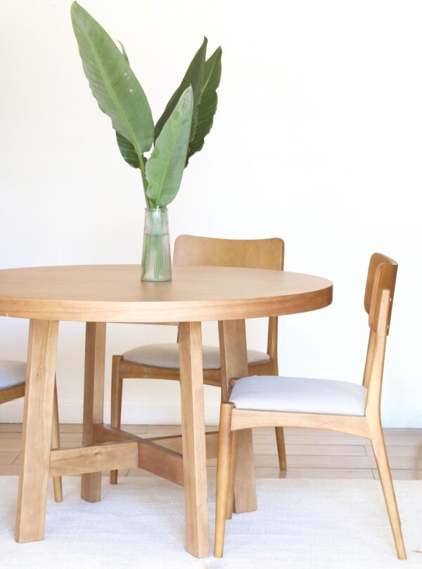illa Bjordal de guatambú, respaldo curvo y asiento tapizado gris; vista lateral en comedor de estilo nórdico.