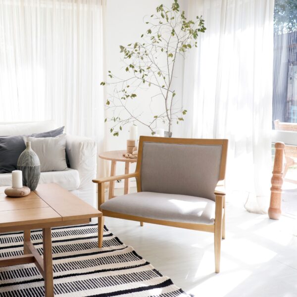 Butacón Olsen de madera clara y tapizado en tela gris.