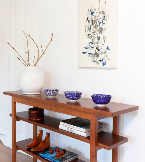Consola Máximo de madera lenga estilo minimalista con tres estantes, decoración con jarrón blanco y cuadros.