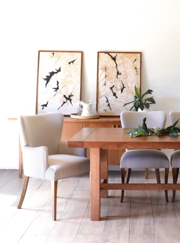 Silla Oporto con brazo de madera guatambú, diseño elegante y cómodo, tapizada en tono claro junto a mesa de comedor.