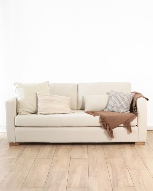 Sillón Cubo Dolores tapizado en tela color natural, diseño minimalista y moderno con patas de madera, ideal para living o sala de estar.