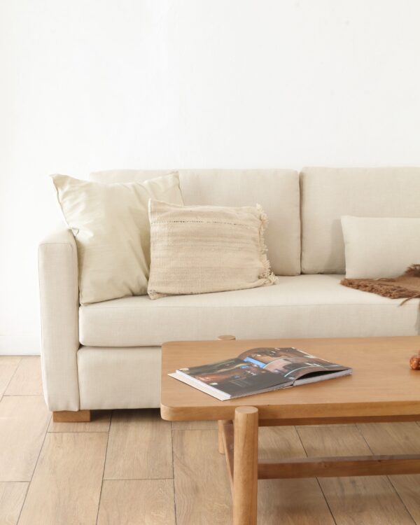 Sillón Cubo Dolores tapizado en tela color natural, diseño minimalista con apoyabrazos rectos y patas de madera.