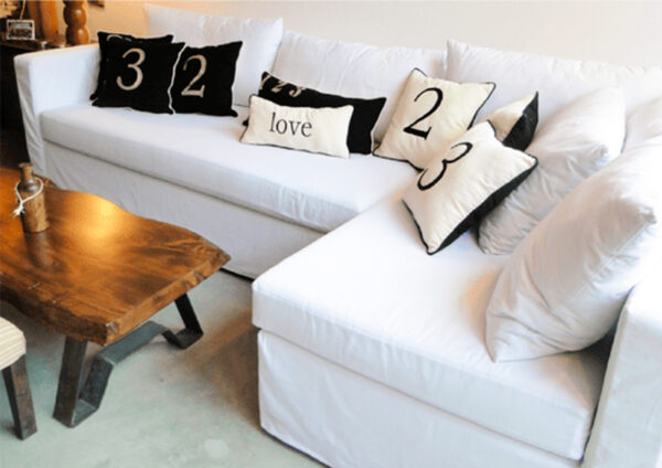 Sillón Esquinero en color blanco con almohadones, estilo minimalista.