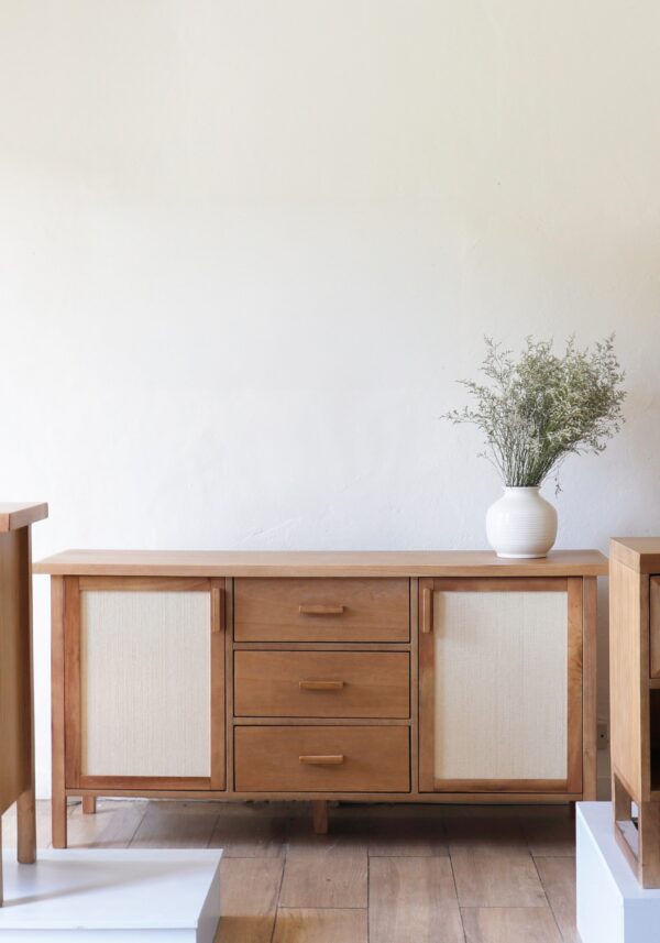 Mueble aparador Berna bajo de madera kiri y rafia, diseño escandinavo con estructura simple, tres cajones centrales y puertas laterales.