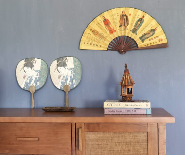 Aparador Bali Bajo en madera de lenga con paneles de rafia, estilo sudeste asiático y clásico, ambientado con lámpara metálica y jarrón decorativo.
