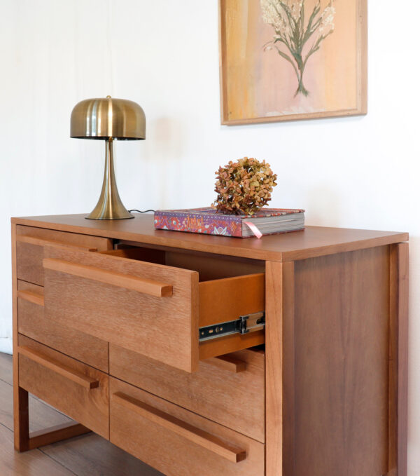 Cómoda Barcelona de madera kiri diseño moderno con cajón abierto mostrando correderas metálicas.
