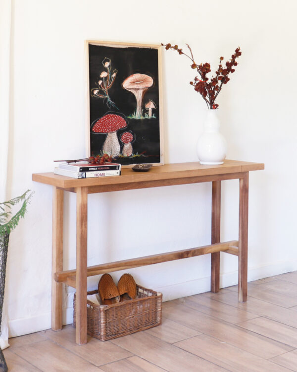 Consola Provance de madera kiri estilo clásico, decorada con libros y jarrón blanco con ramas.