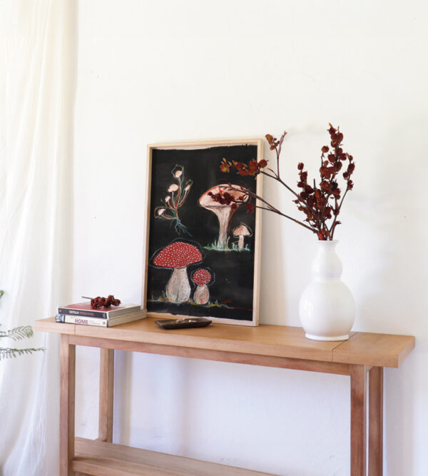 Consola Bjordal de madera kiri cálida, decorada con jarrón blanco y ramas secas, estilo moderno.