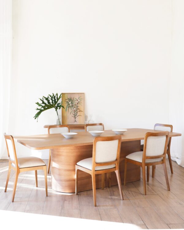 Mesa de comedor Lanín en madera kiri estilo contemporáneo con seis sillas tapizadas y vajilla blanca sobre la superficie