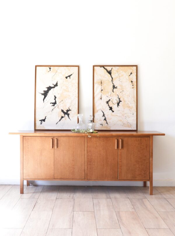 Vajillero Máximo de madera lenga, diseño sobrio con líneas rectas, acompañado de cuadros decorativos y objetos de vidrio.