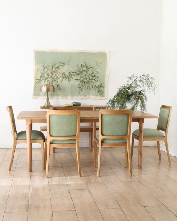 Vista completa de la mesa de comedor Madrid en madera kiri estilo nórdico con seis sillas tapizadas y ambiente minimalista con lámpara dorada