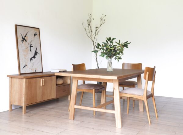 Vista completa de la mesa de comedor Oslo en madera kiri estilo hygge acompañada por cuatro sillas de diseño nórdico y aparador de fondo