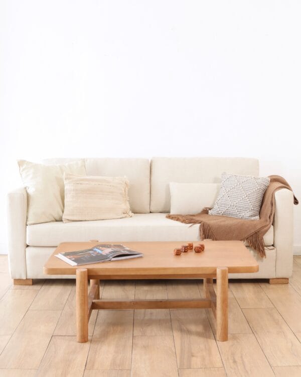 Mesa de living Madrid Frente en madera kiri, estilo sobrio, frente a un sofá claro con almohadones neutros, sobre piso de madera clara.