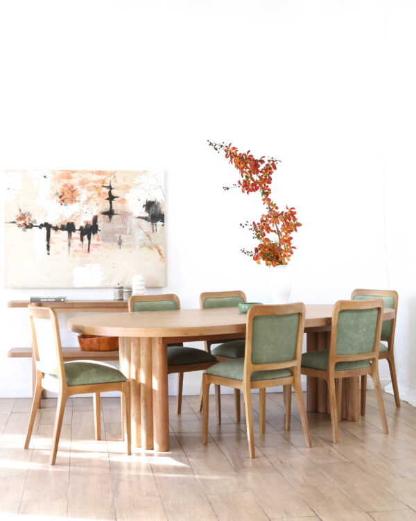 Vista completa de la mesa Nórdica en madera kiri estilo escultórico rectangular con seis sillas verdes y ambiente decorativo minimalista