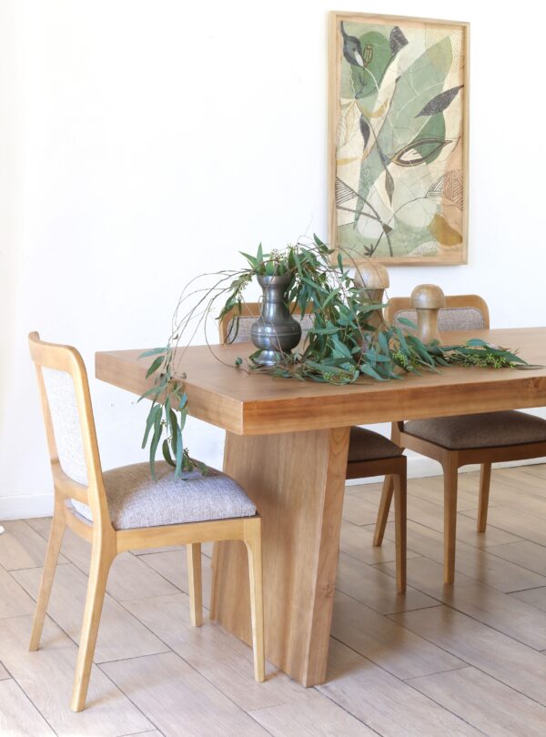Vista lateral de la mesa de comedor Serbia en madera kiri estilo japandi con centro de mesa en jarrón metálico y follaje verde