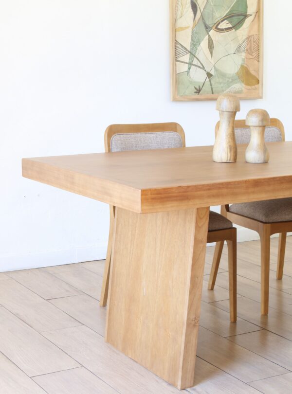 Detalle de la mesa de comedor Serbia en madera kiri estilo japandi con base ancha y dos sillas tapizadas en tono claro