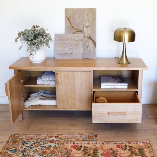 Aparador Oslo de madera kiri en estilo escandinavo, con cajón abierto y puertas entreabiertas, mostrando su capacidad de guardado y diseño funcional.