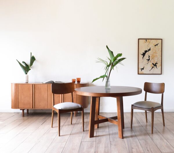 Mesa Provance redonda en madera lenga estilo campiña francesa acompañada por dos sillas de respaldo curvo y aparador de fondo