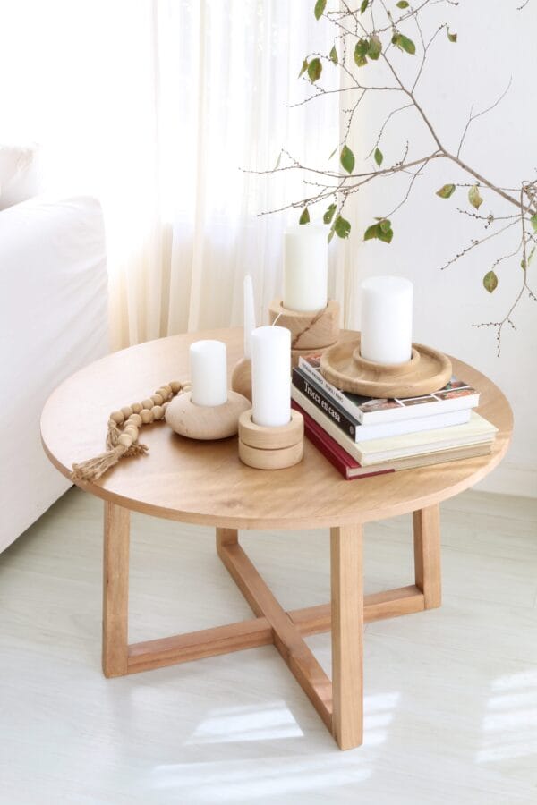 Mesa auxiliar redonda Bjordal de madera kiri estilo minimalista, con velas y libros decorativos sobre su superficie.