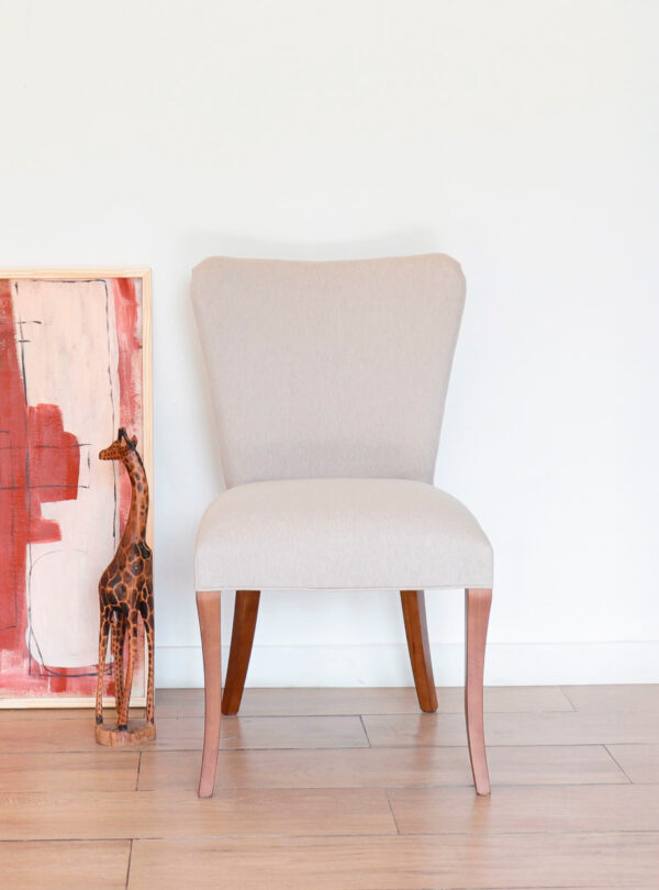 Silla Oporto de guatambú con respaldo curvo y tapizado beige, sobre piso de madera clara, estilo atemporal.