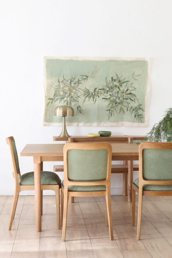Silla Tulum de madera guatambú, con estructura robusta y respaldo y asiento tapizados en tela verde. Estilo elegante.