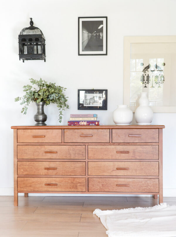 Cómoda Máximo de madera lenga estilo atemporal con ocho cajones, decorada con jarrones blancos y libros sobre su superficie.
