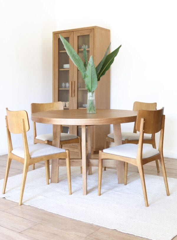 Conjunto de comedor con mesa Provance redonda en madera kiri estilo campiña francesa rodeada de cuatro sillas tapizadas en lino claro